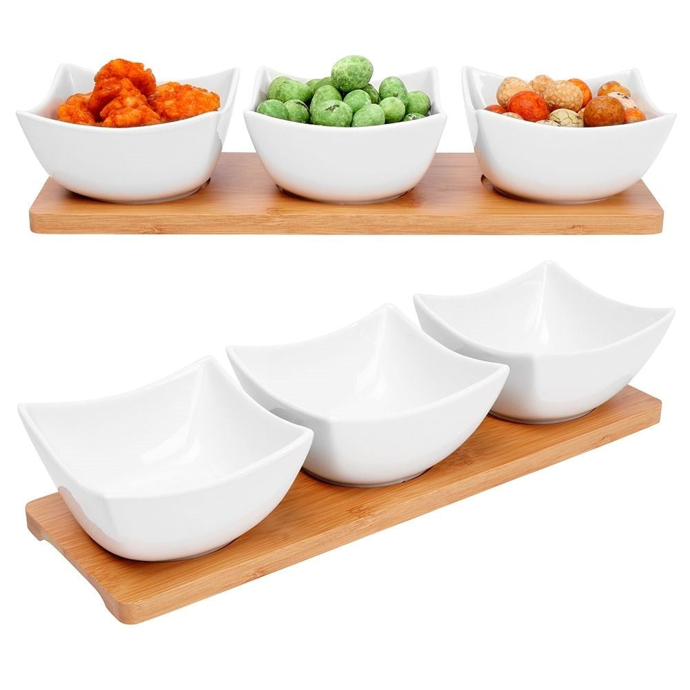 Three elegant porcelain bowls on a bamboo tray for snacks and dips