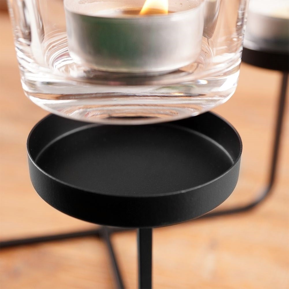 Elegant candle holder in black metal with four glass inserts