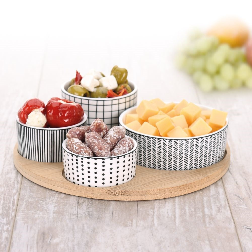 Four porcelain bowls on a bamboo tray for serving goodies