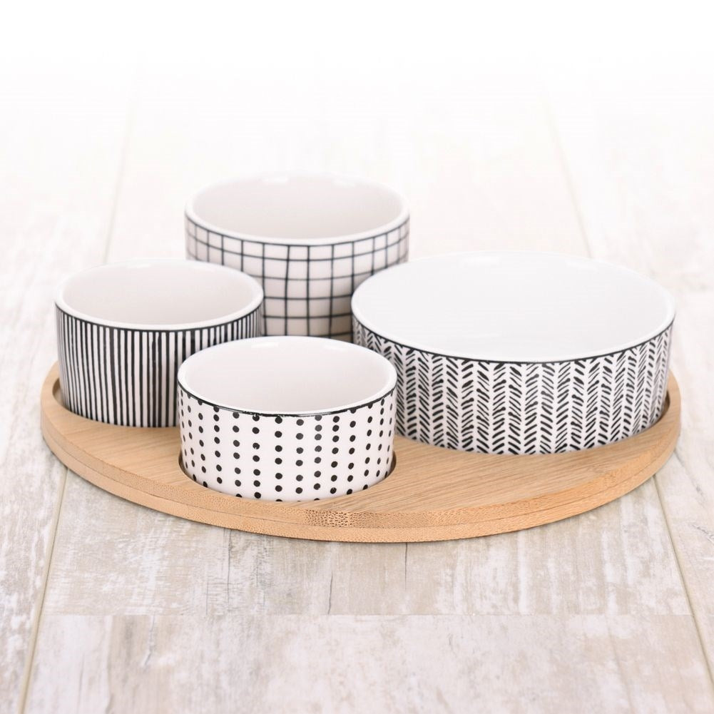 Four porcelain bowls on a bamboo tray for serving goodies