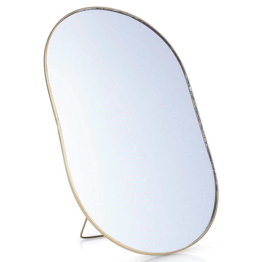 Oval cosmetic mirror on stand in luxurious gold color
