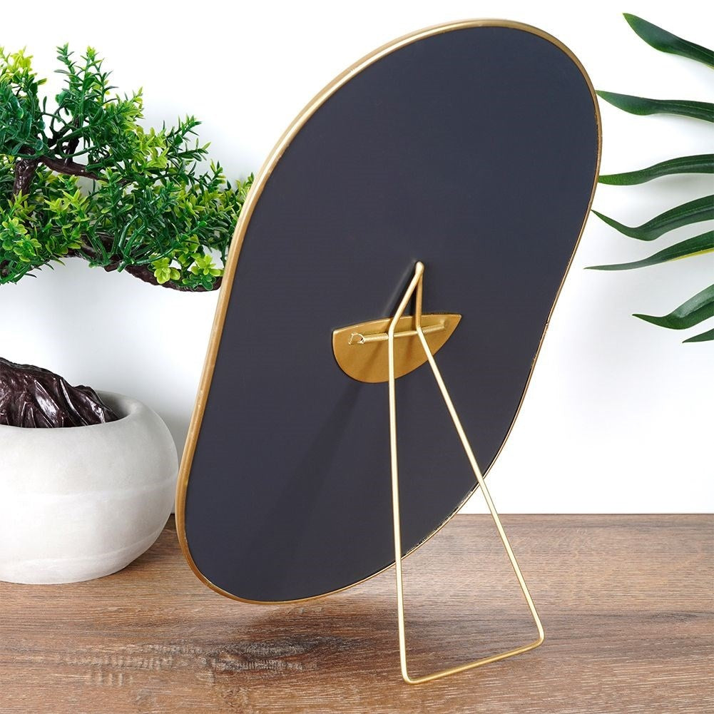 Oval cosmetic mirror on stand in luxurious gold color