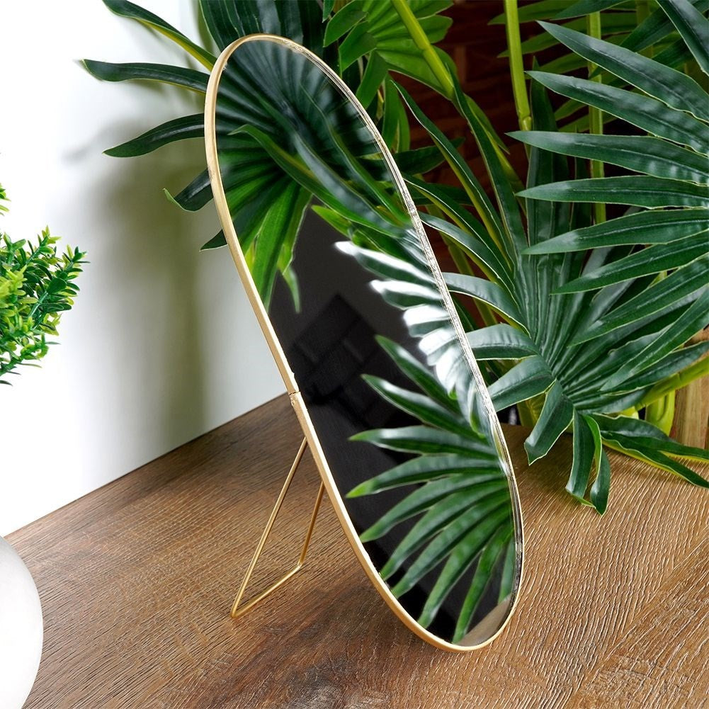Oval cosmetic mirror on stand in luxurious gold color