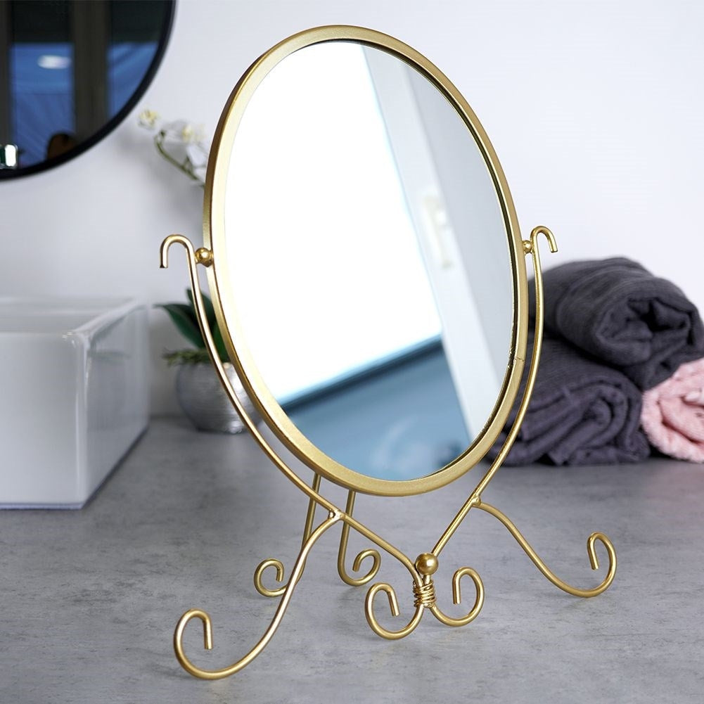 Oval make-up mirror on stand in luxurious gold color