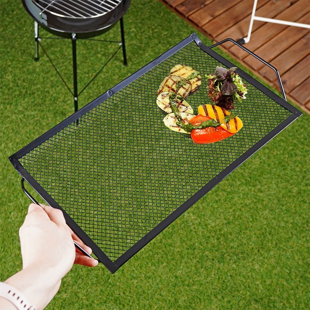 Perforated grill plate in black metal for meat and vegetables