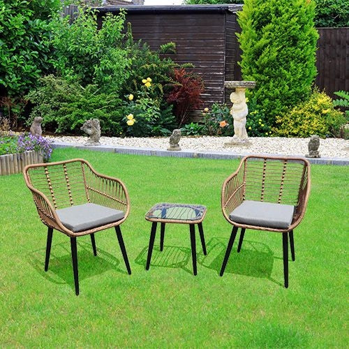 Rattan garden furniture set with chairs and a table with a glass top