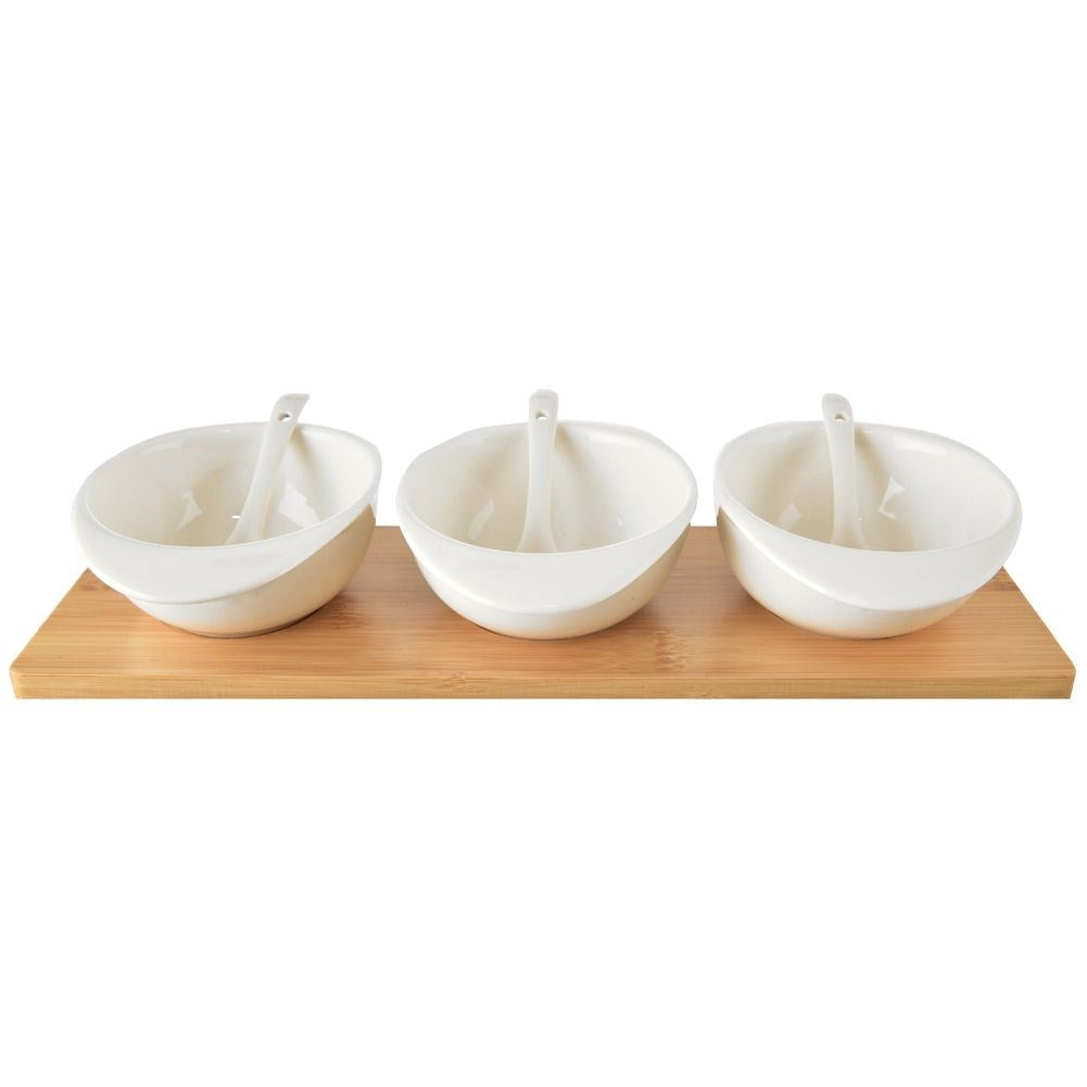 Set of three porcelain bowls and spoons on a bamboo tray