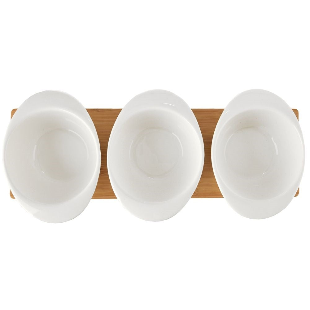 Set of three porcelain bowls and spoons on a bamboo tray