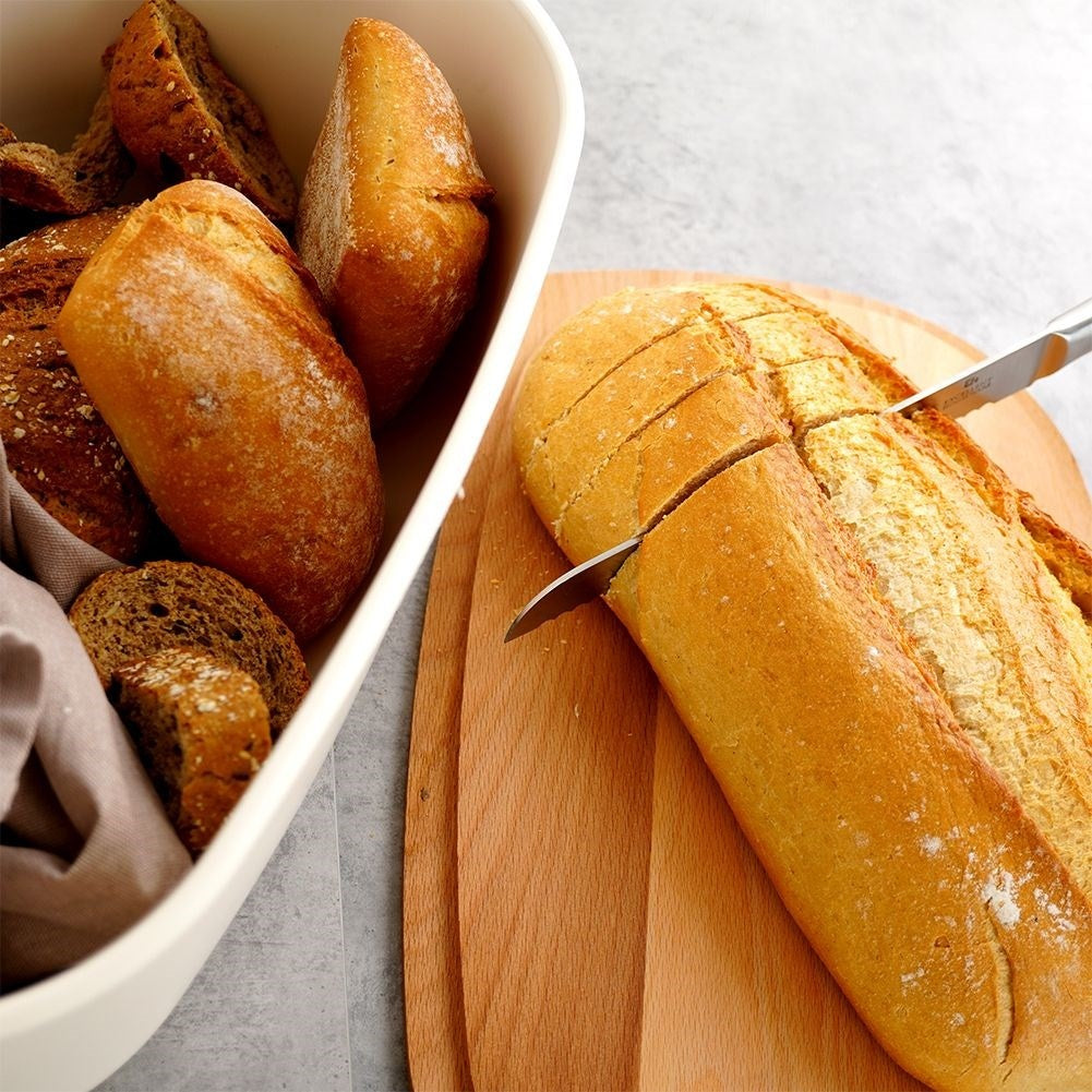 Spacious cream colored bread box with wooden cutting board