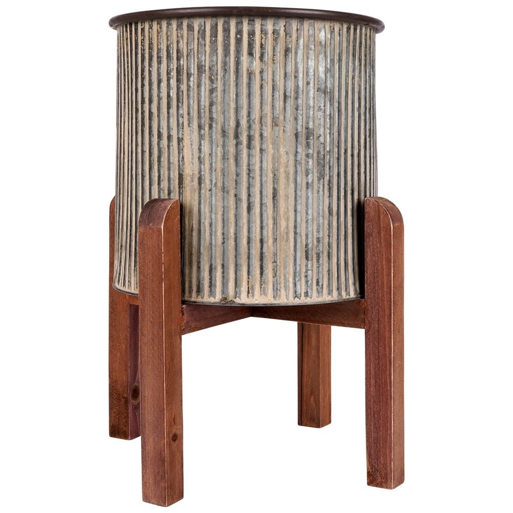 Steel flower pot with grooved surface on a wooden stand