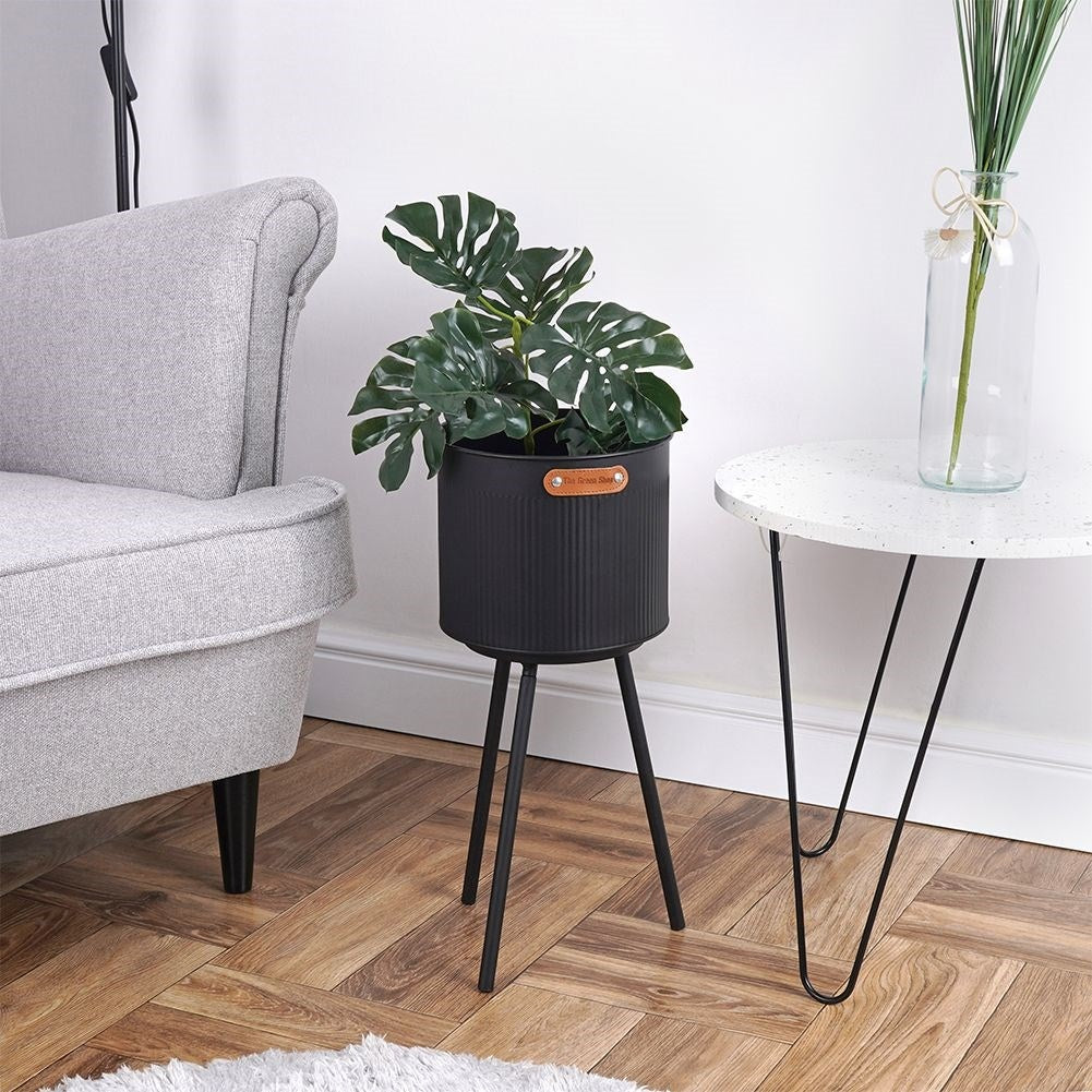 Stylish black metal pot with grooved surface and three legs