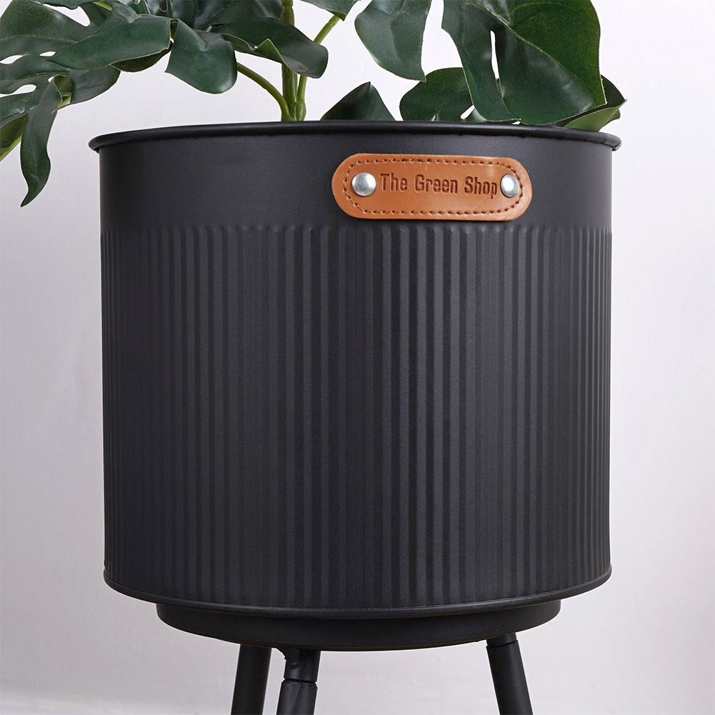 Stylish black metal pot with grooved surface and three legs