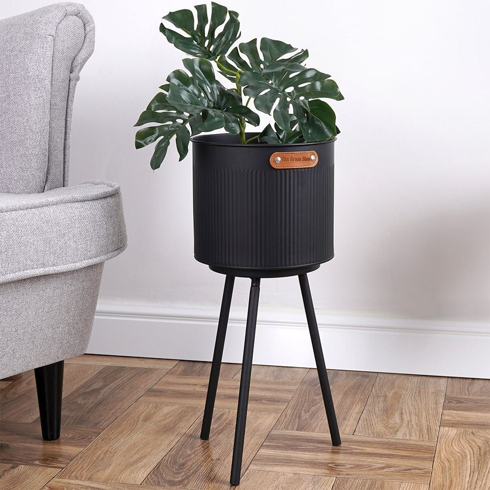 Stylish black metal pot with grooved surface and three legs