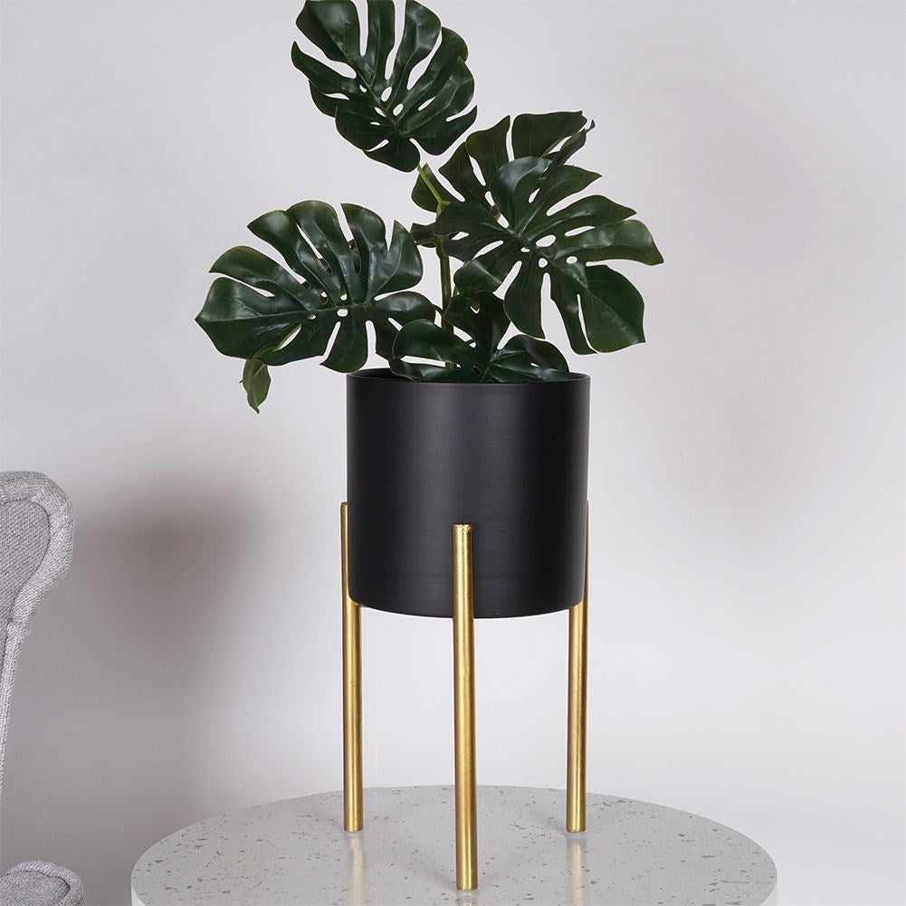 Stylish metal pot on stand in black and gold for plants