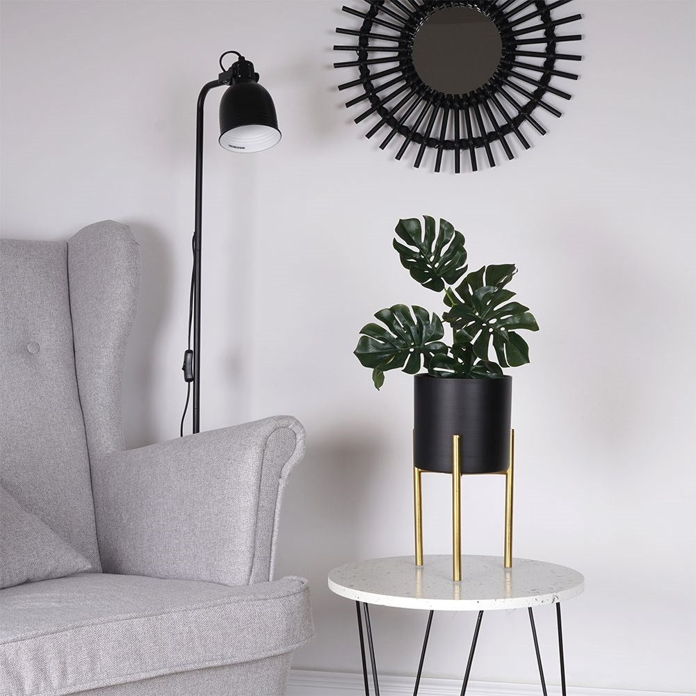 Stylish metal pot on stand in black and gold for plants