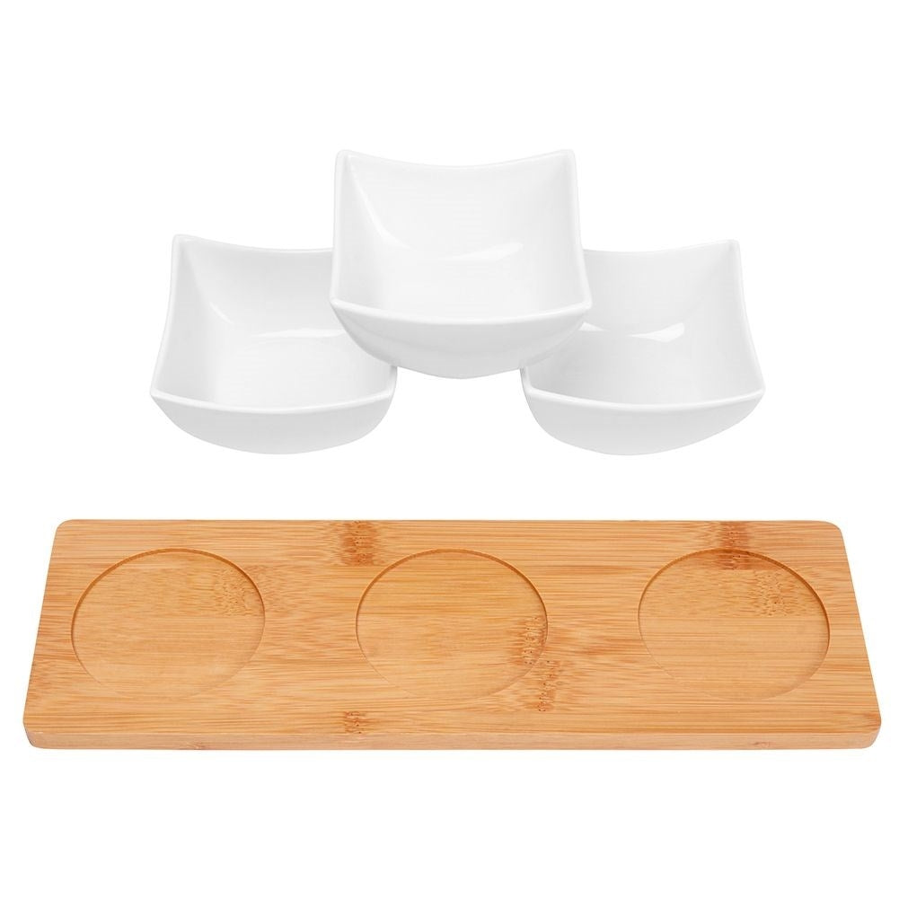 Three elegant porcelain bowls on a bamboo tray for snacks and dips
