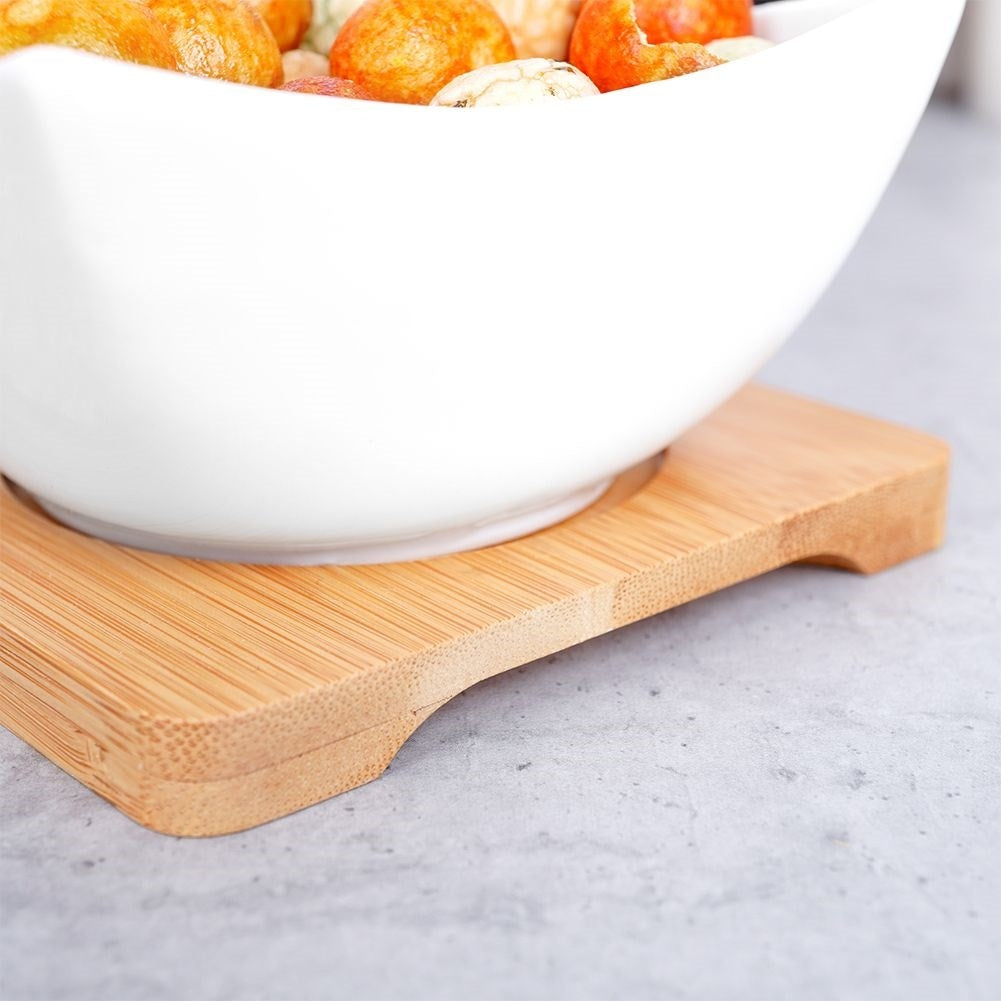 Three elegant porcelain bowls on a bamboo tray for snacks and dips