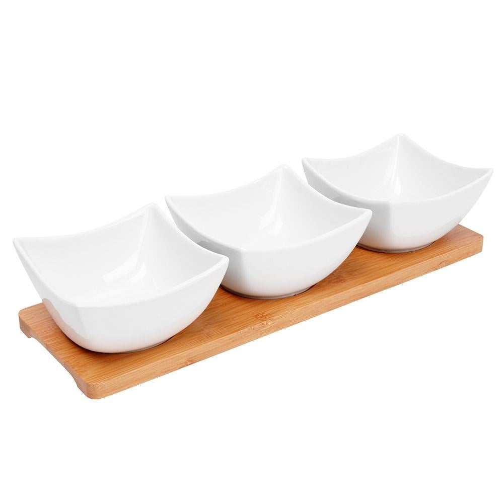 Three elegant porcelain bowls on a bamboo tray for snacks and dips