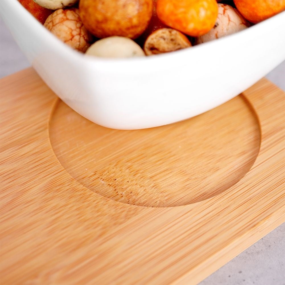 Three elegant porcelain bowls on a bamboo tray for snacks and dips