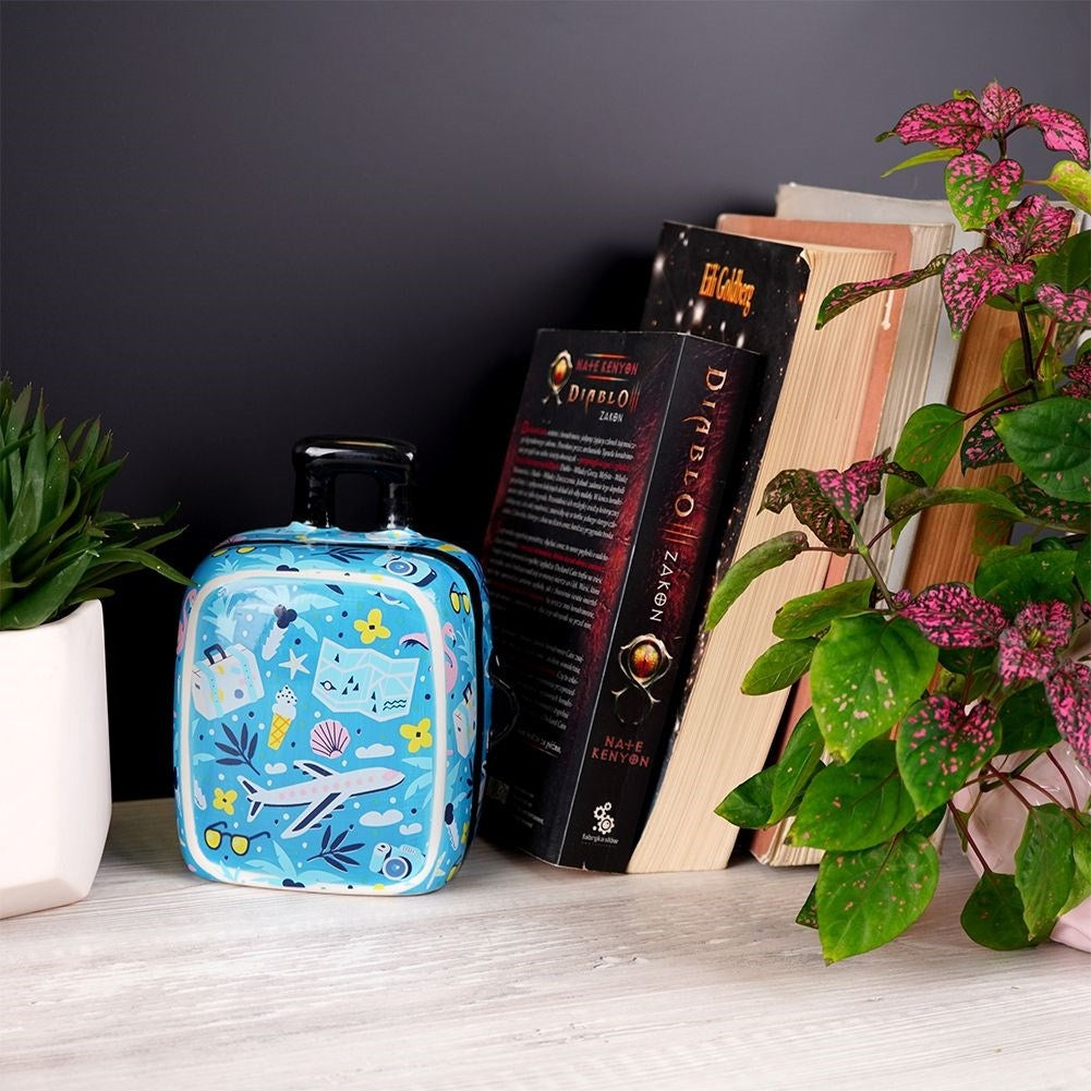 Travel bag-shaped piggy bank in blue ceramic with travel details