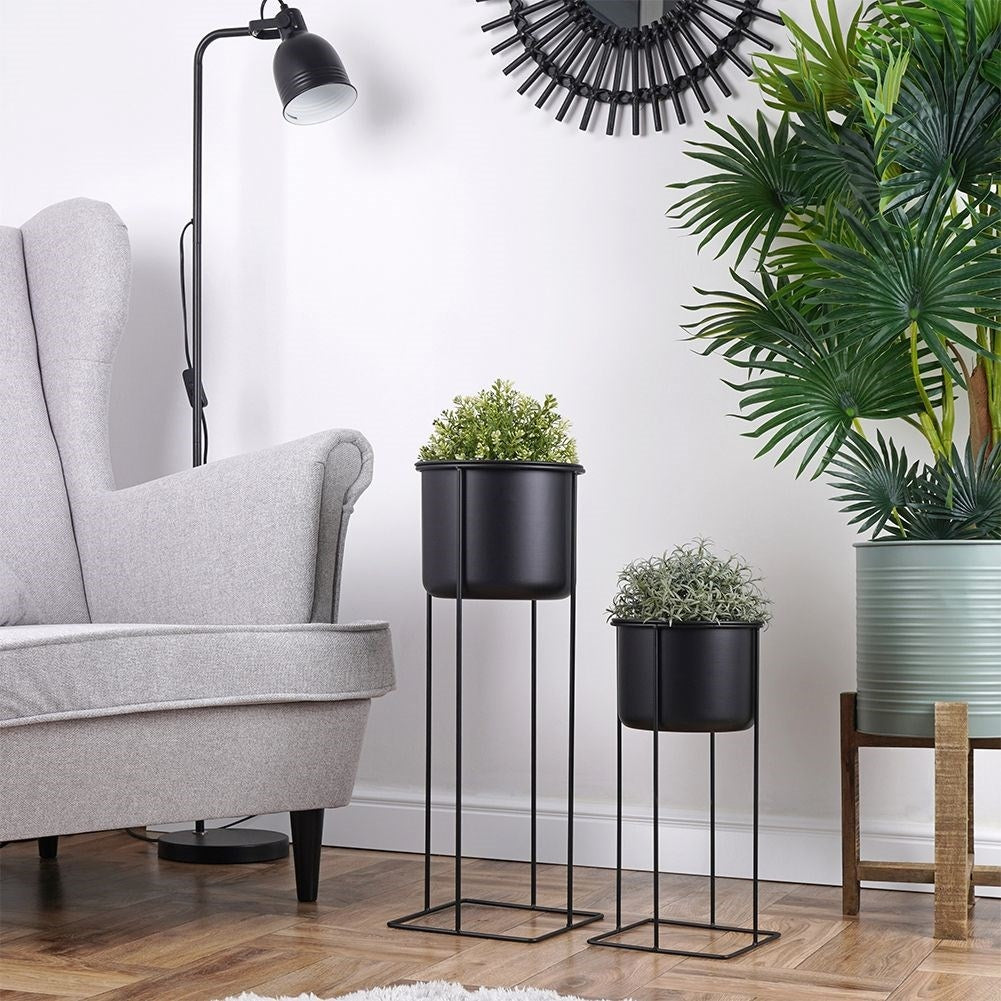 Two black metal pots with stands, different sizes