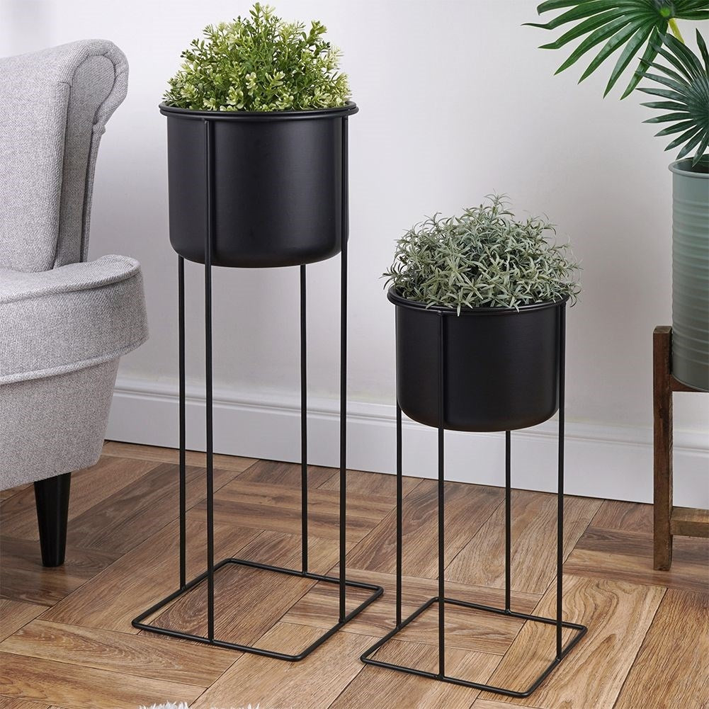 Two black metal pots with stands, different sizes