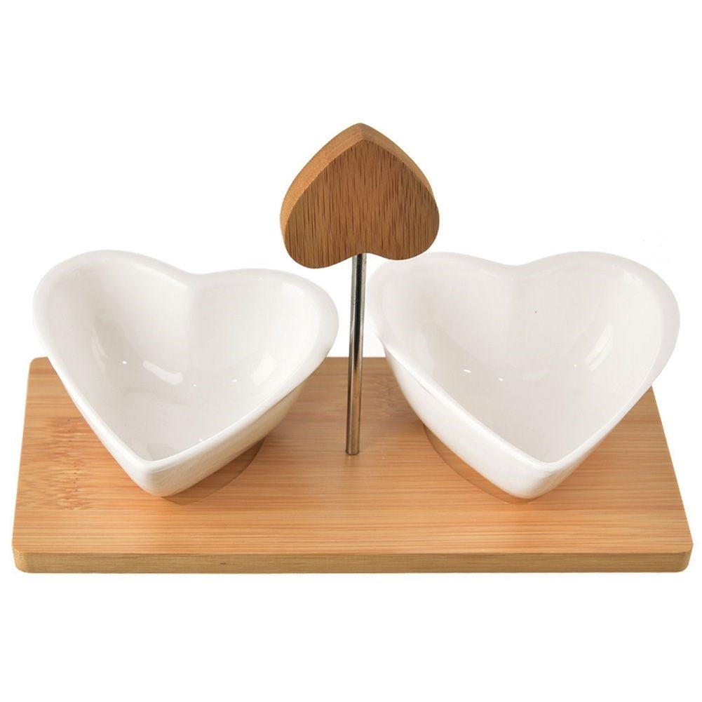 Two heart-shaped porcelain bowls on a bamboo tray for serving