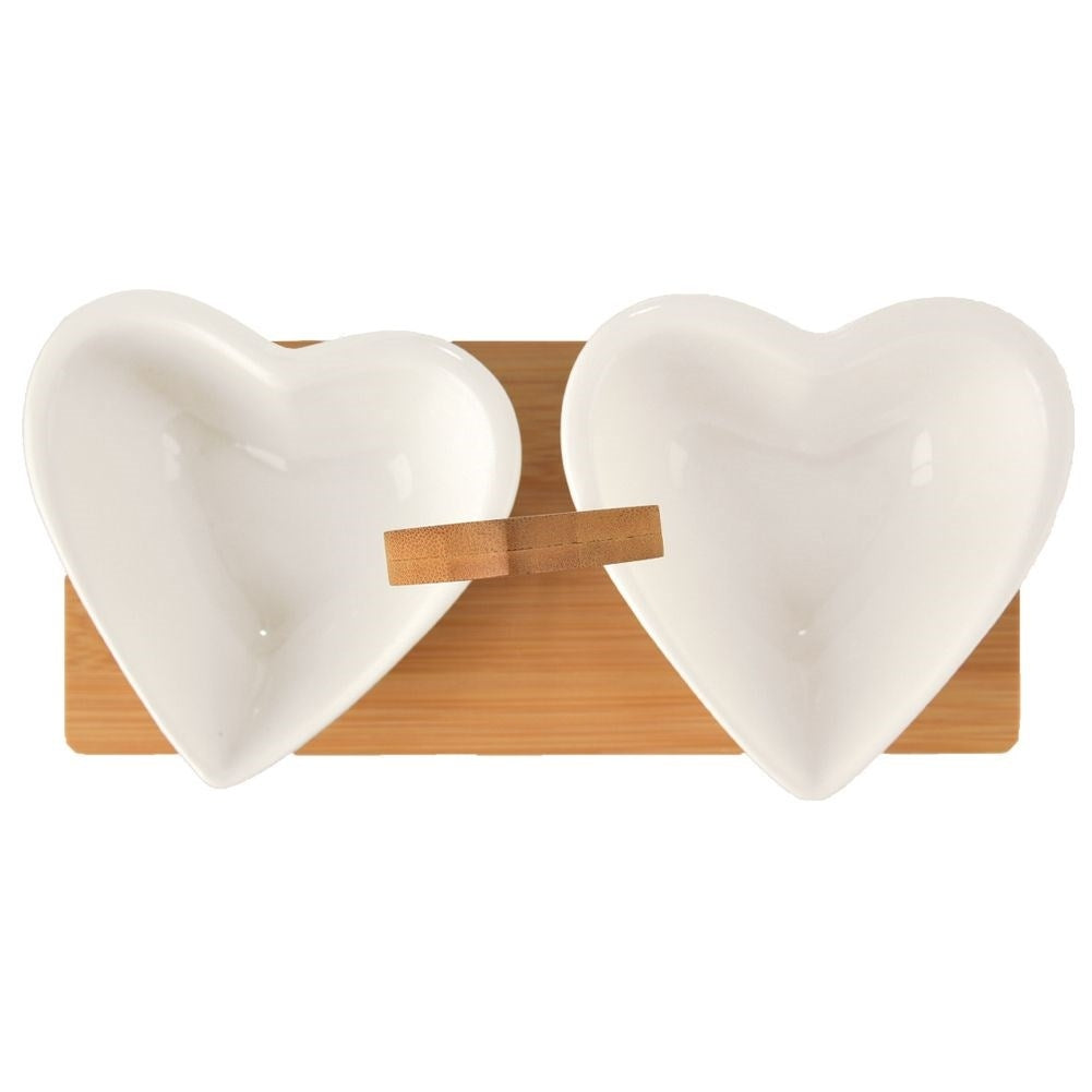 Two heart-shaped porcelain bowls on a bamboo tray for serving